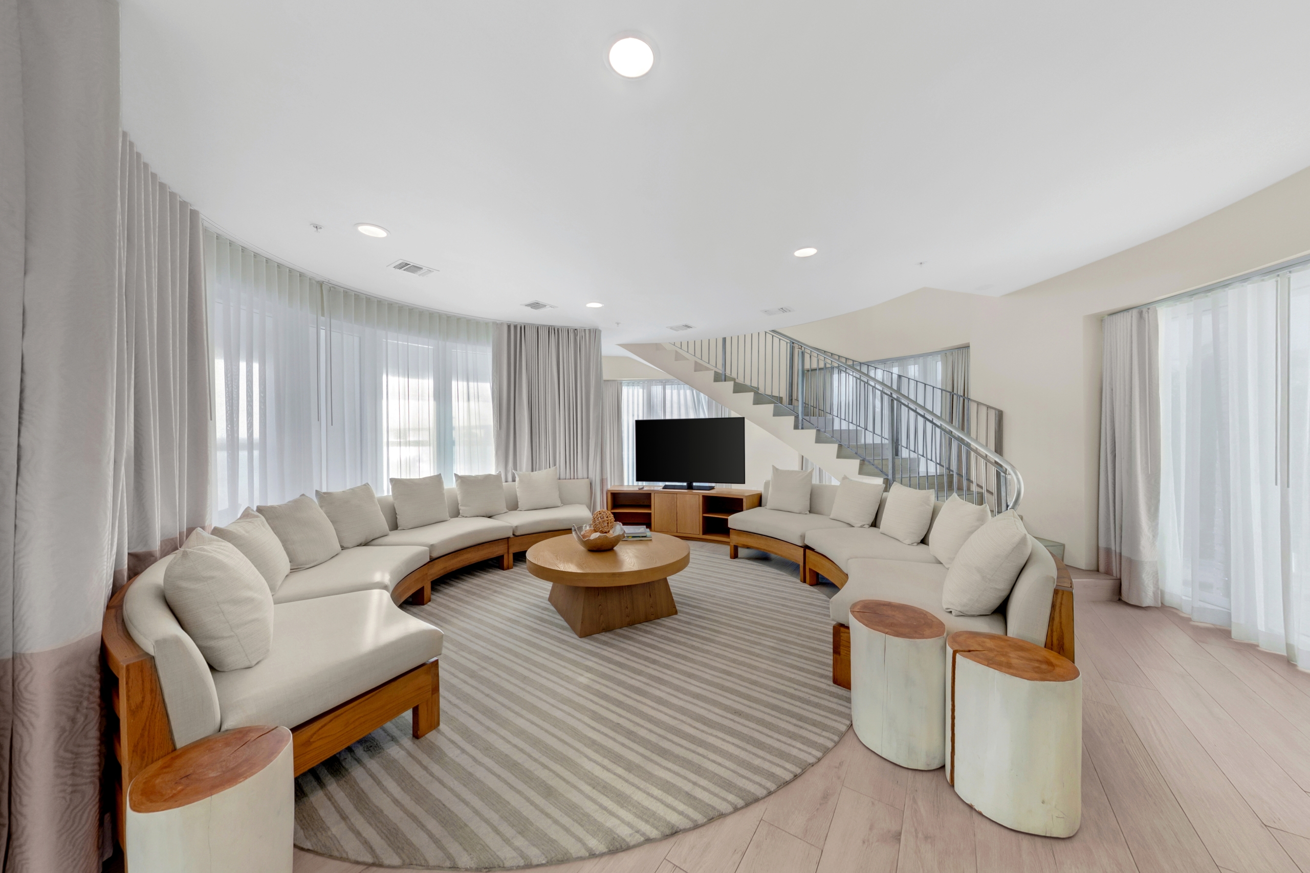 large circular room with two semi circular couches on both sides of a large TV.