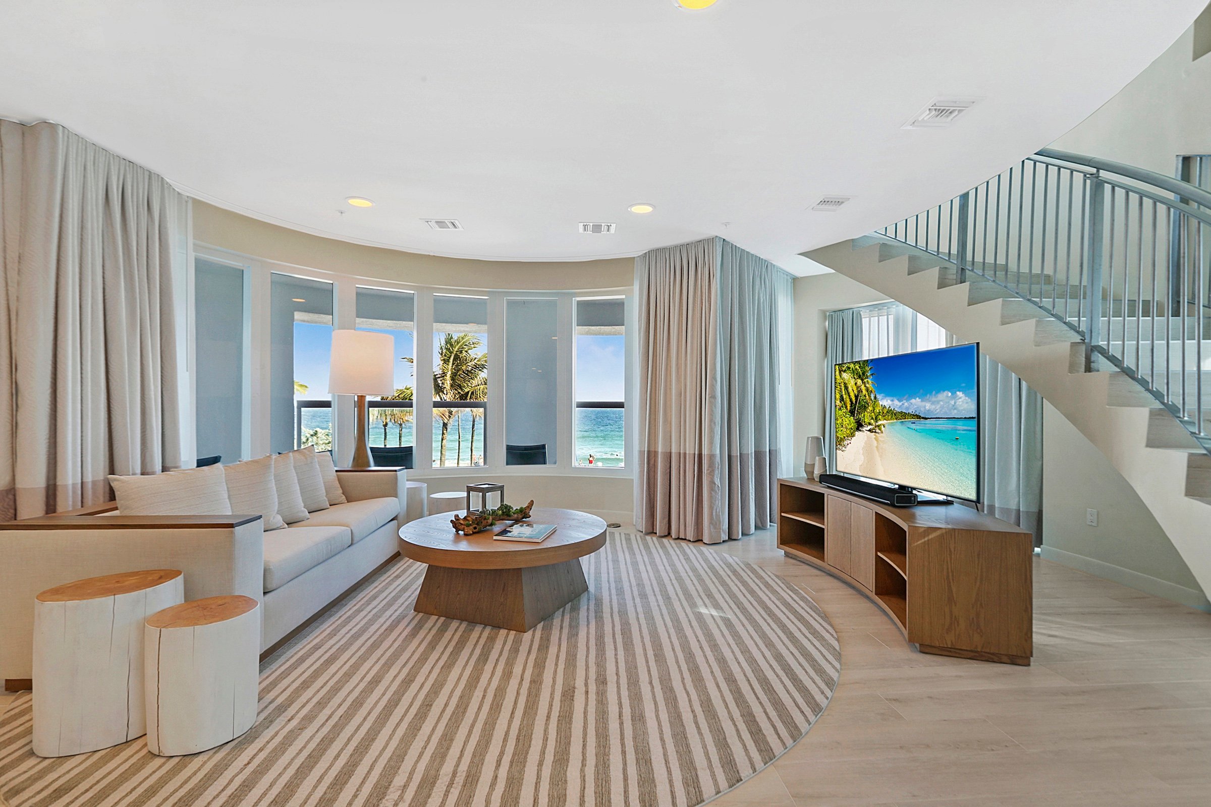A large circular sitting room with a spiral staircase and an ocean front balcony