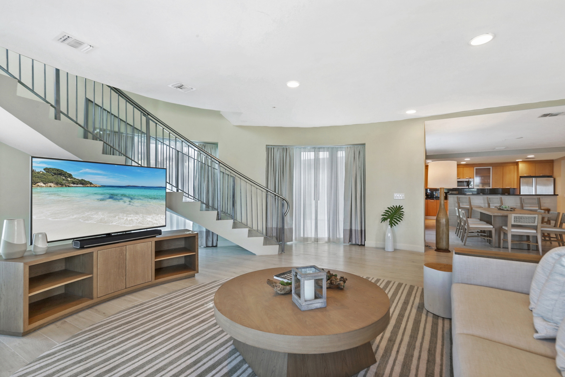A large circular sitting room with a spiral staircase and an ocean front balcony
