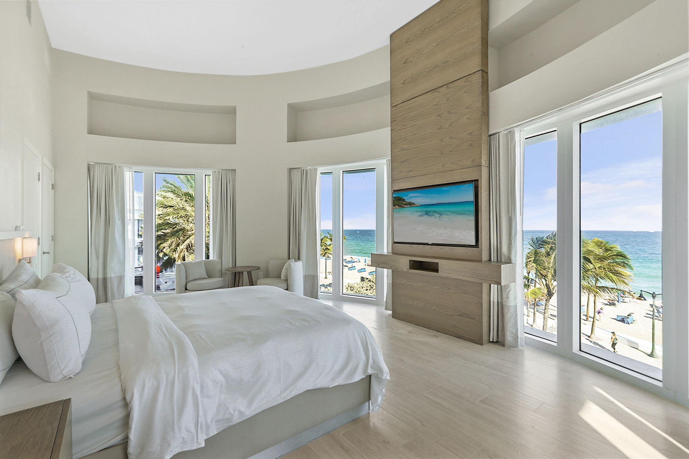 A large circular bedroom looking out on the ocean, wth a wall mounted television.