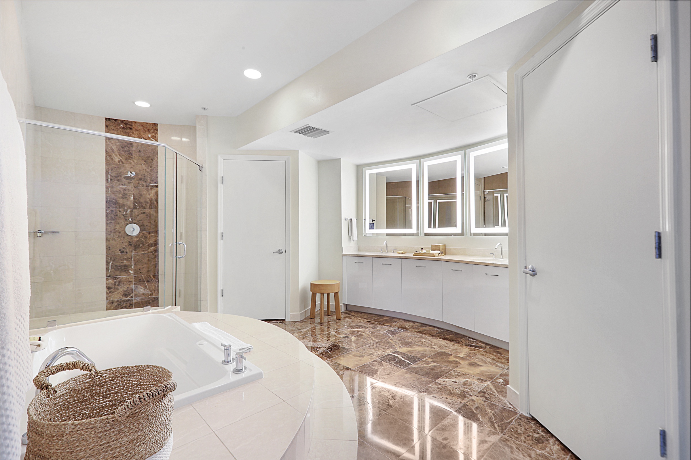 A large bathroom with marble floors and a separate shower and tub.
