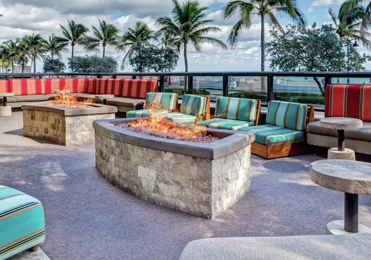 two stone fire pits surrounded by red striped and teal striped seating at the patio of restaurant S3