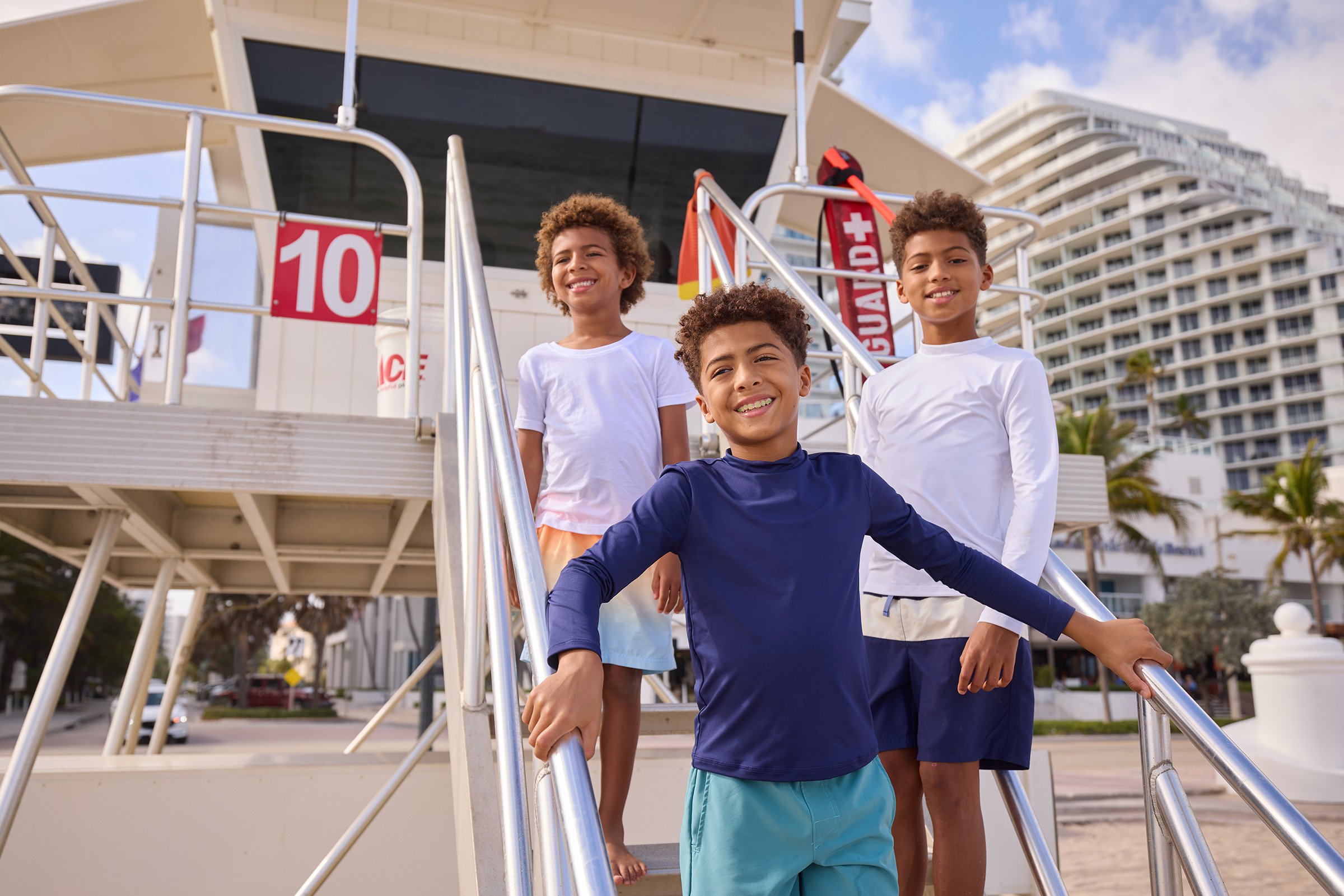 Kids posing at a lifeguard tower on the beach