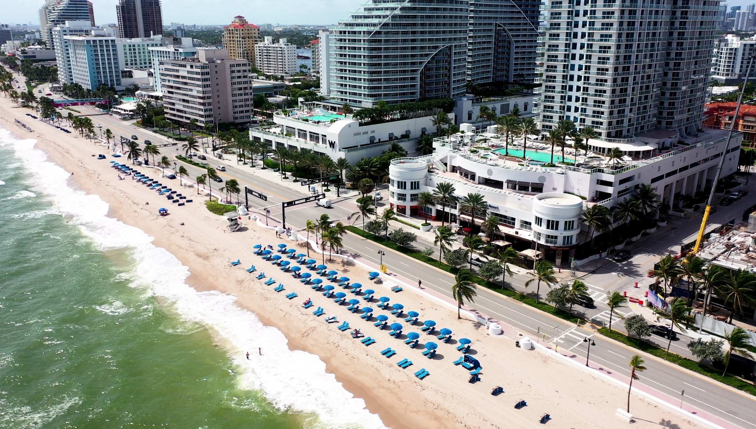 Aerial view of the Fort Lauderdale beach lined with palm trees and blue beach furniture