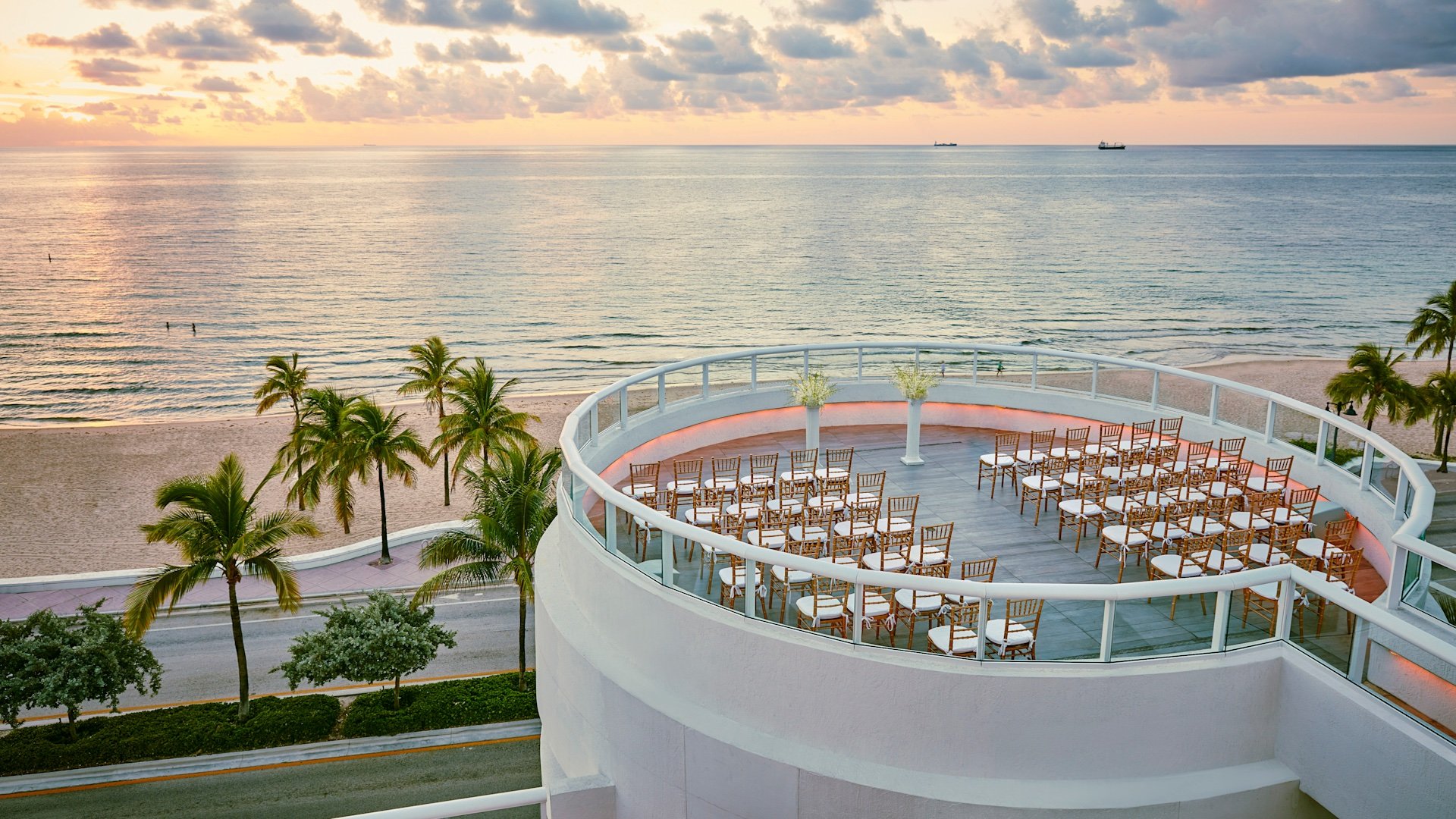 Wooden chairs with white cushions line the sides of a circular rotunda overlooking the ocean