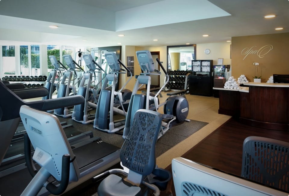A row of treadmills and ellipticals next to the Spa Q fitness center reception desk