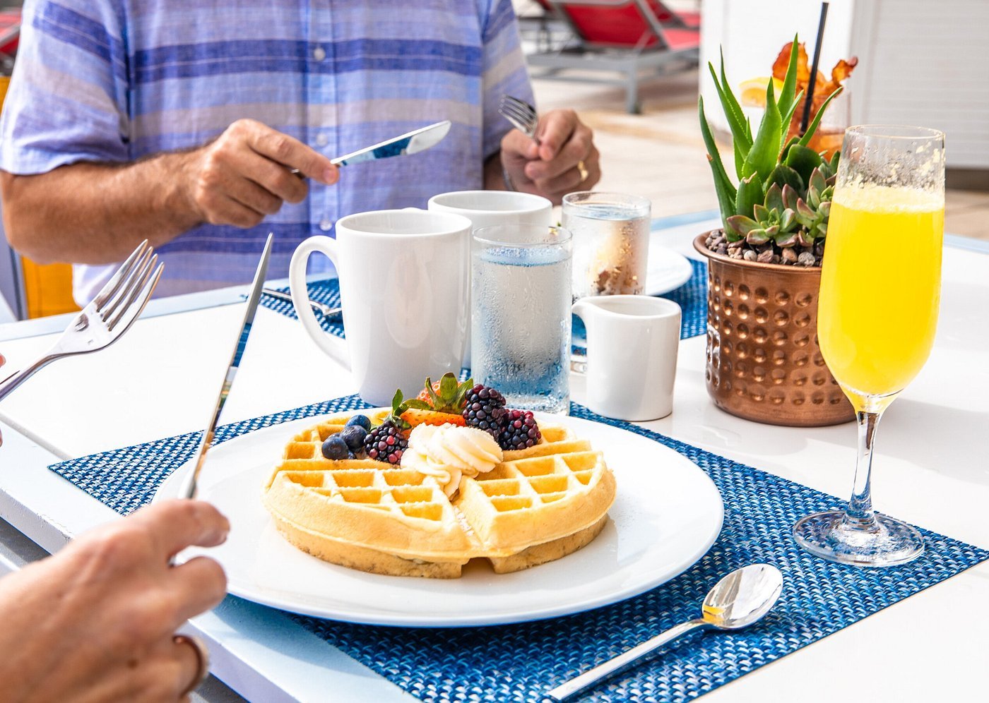 two individuals with utensils in hand ready to eat breakfast