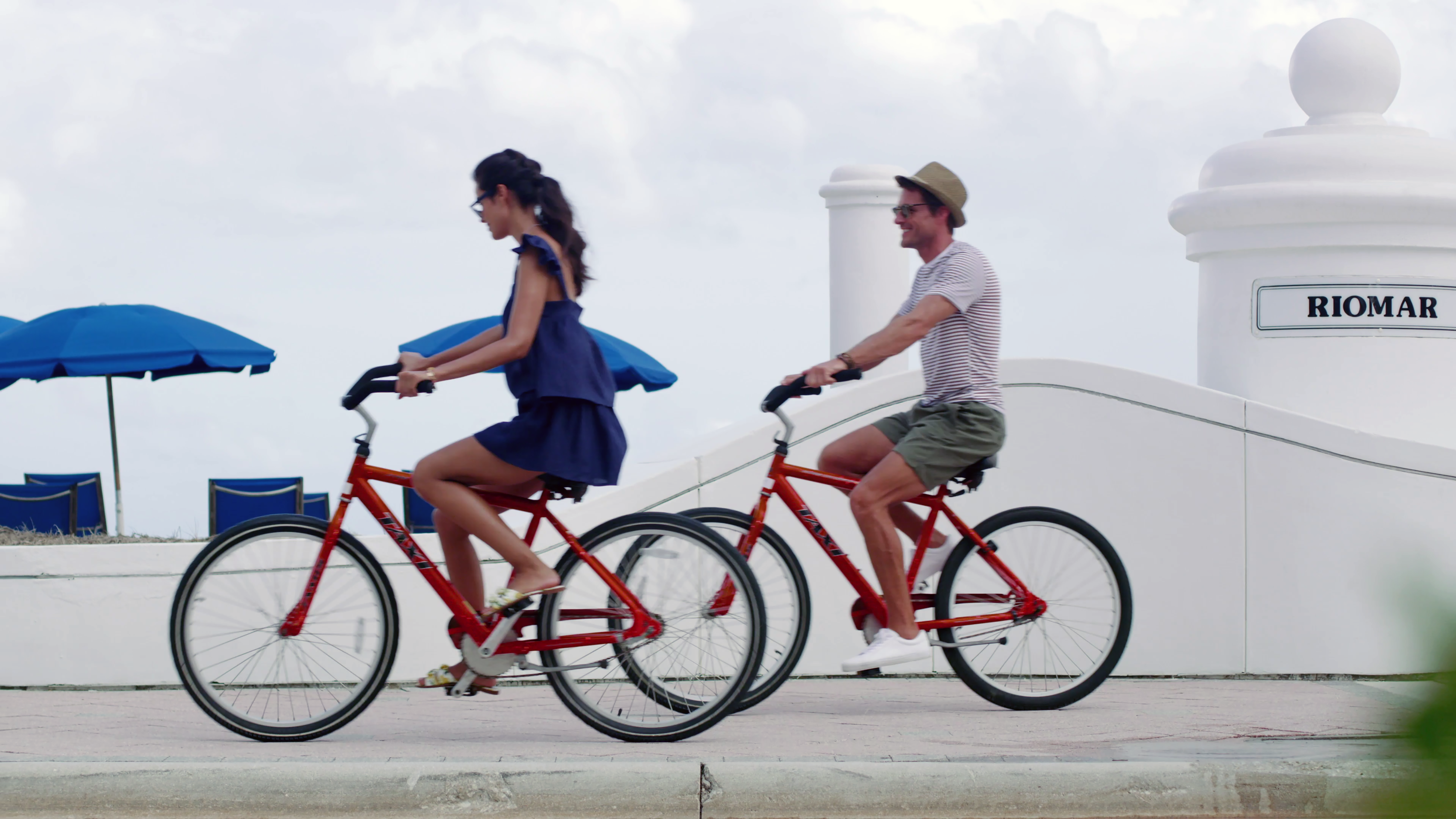 a couple ride red bicycles along the beach