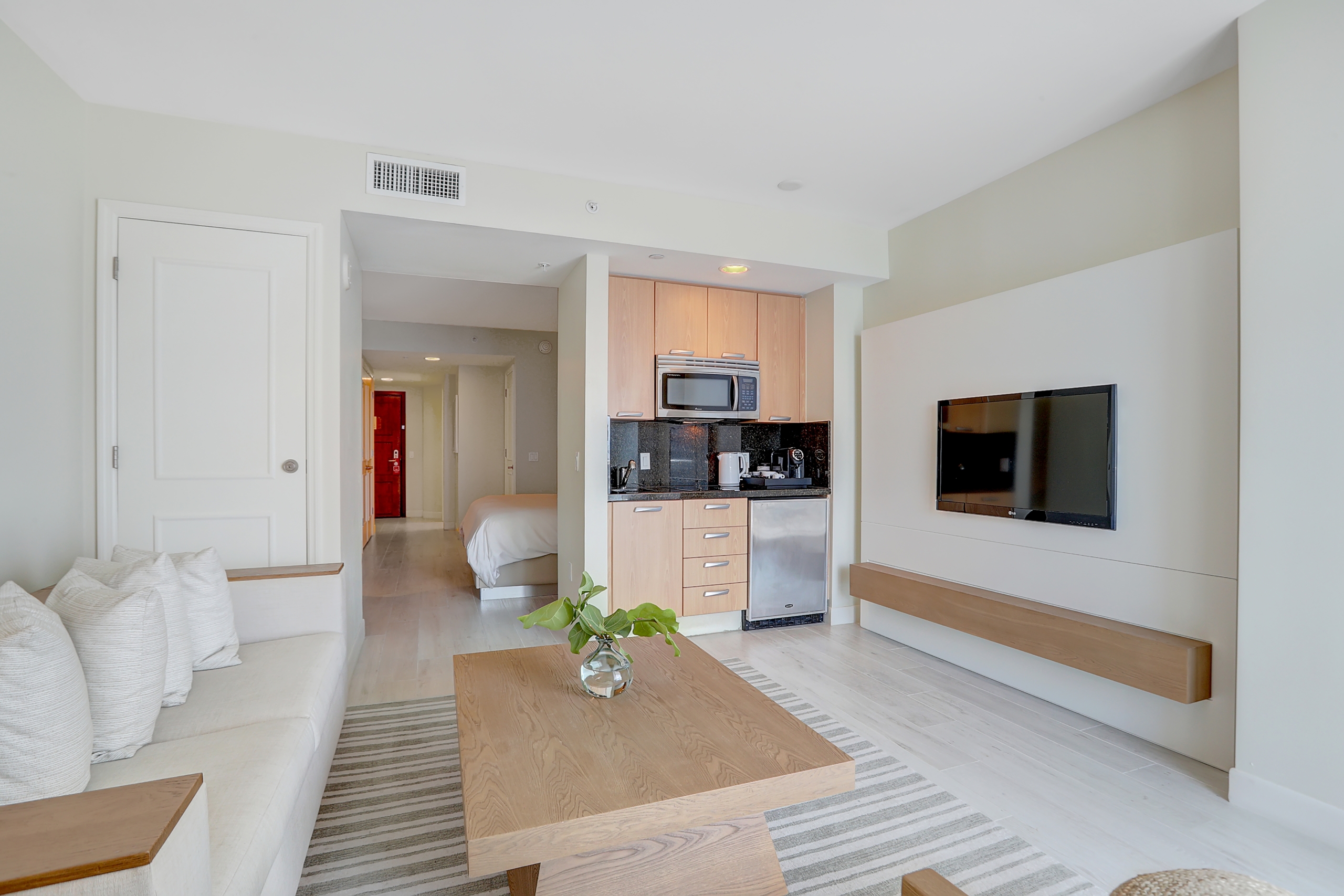 White wooden couch, light wooden tea table, and kitchenettes in modern wide space