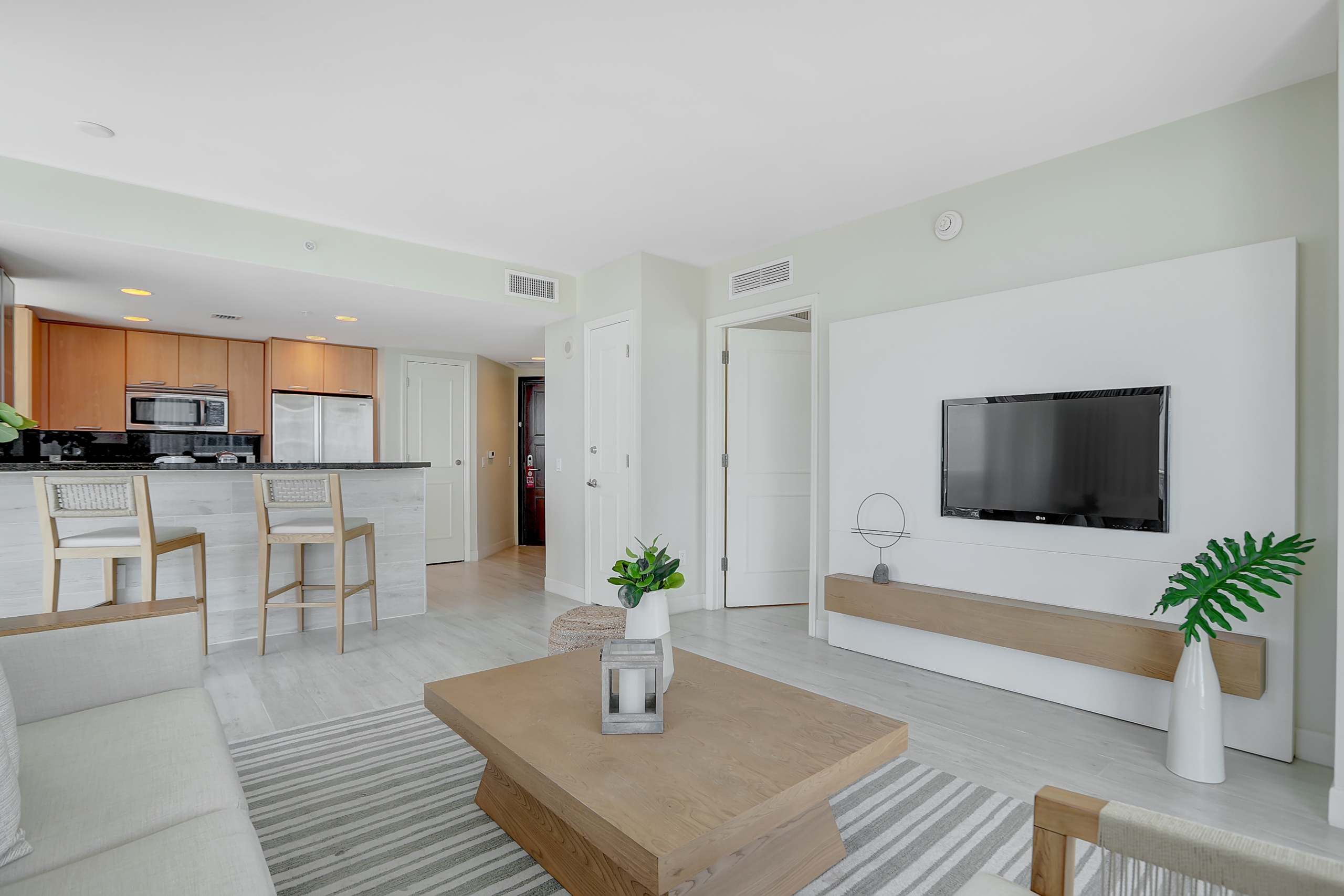 Kitchen space with black counters and wooden shelves and living room with white couch and tea table
