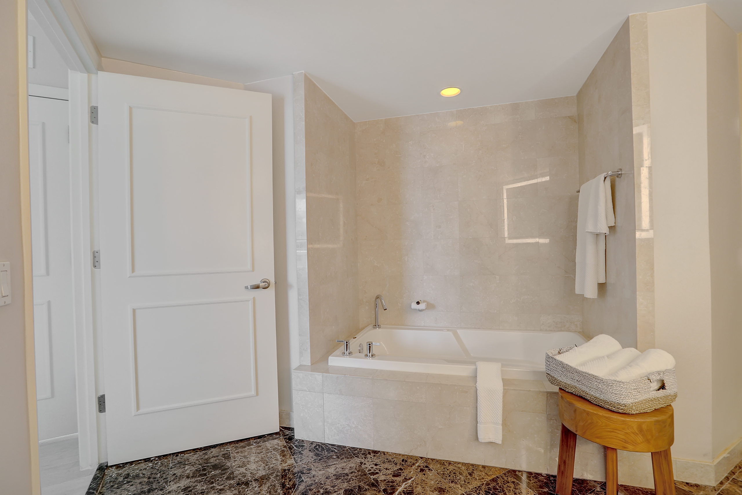 White bathtub and towel amenities in white marble bathroom