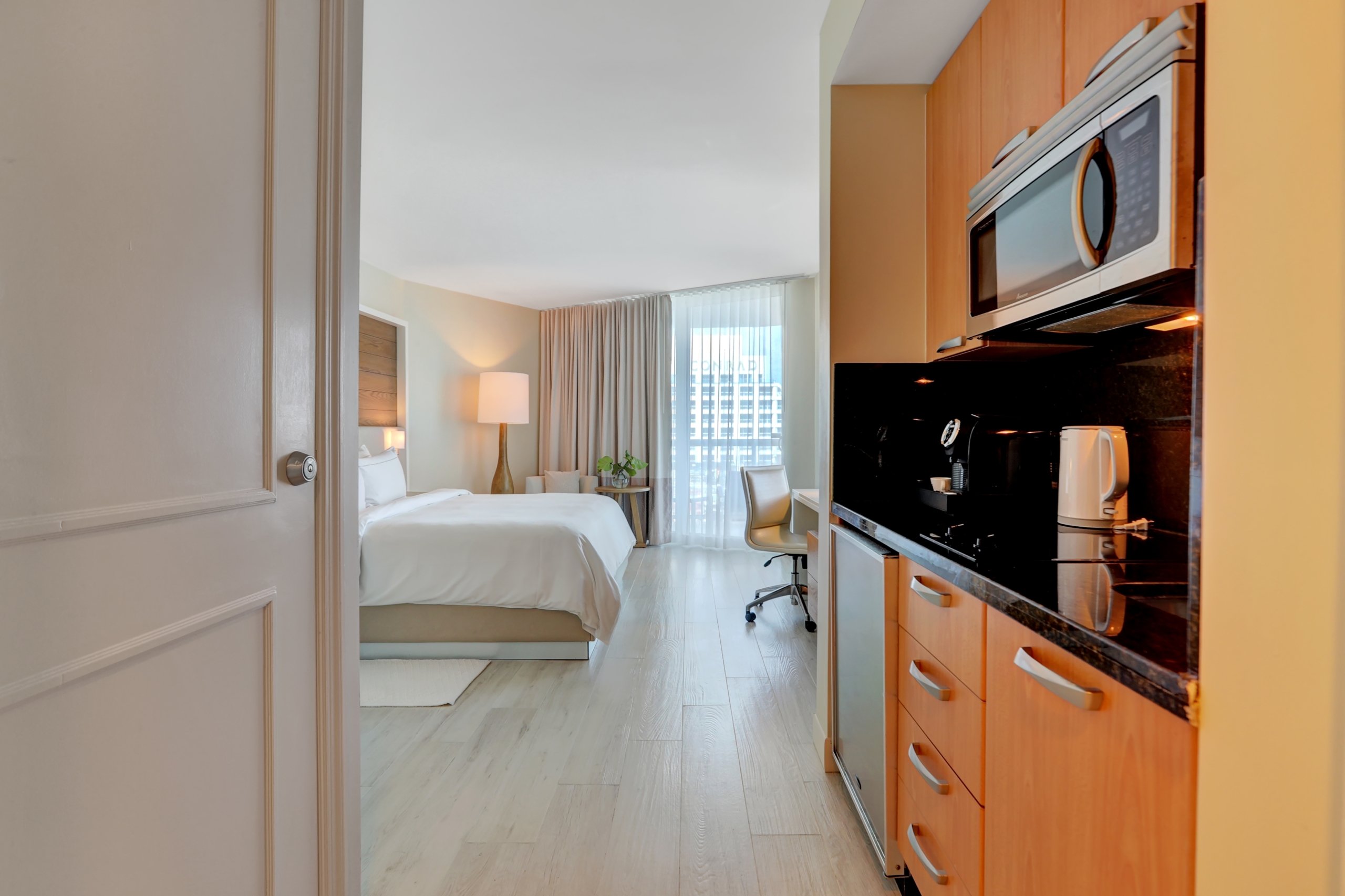 A large bedroom with kitchenettes of black marble counter and orange wooden shelves