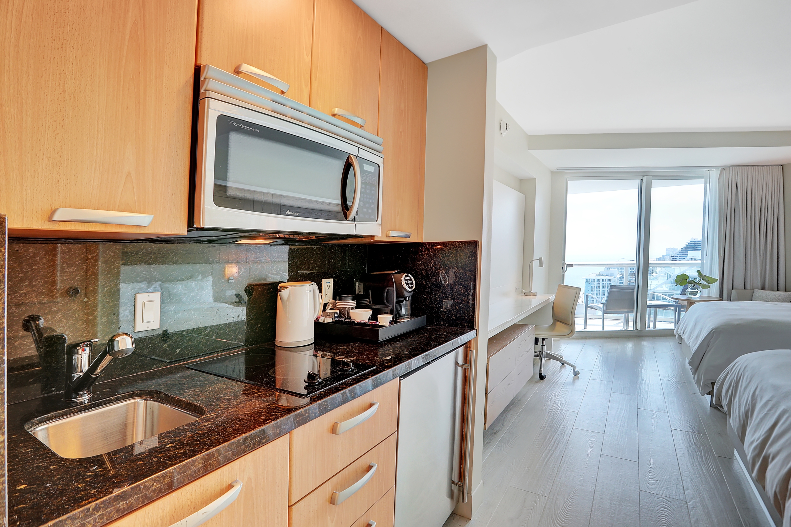 Black counter, wooden shelves for kitchenettes and two qieen beds with tall window to balcony in modern bedroom