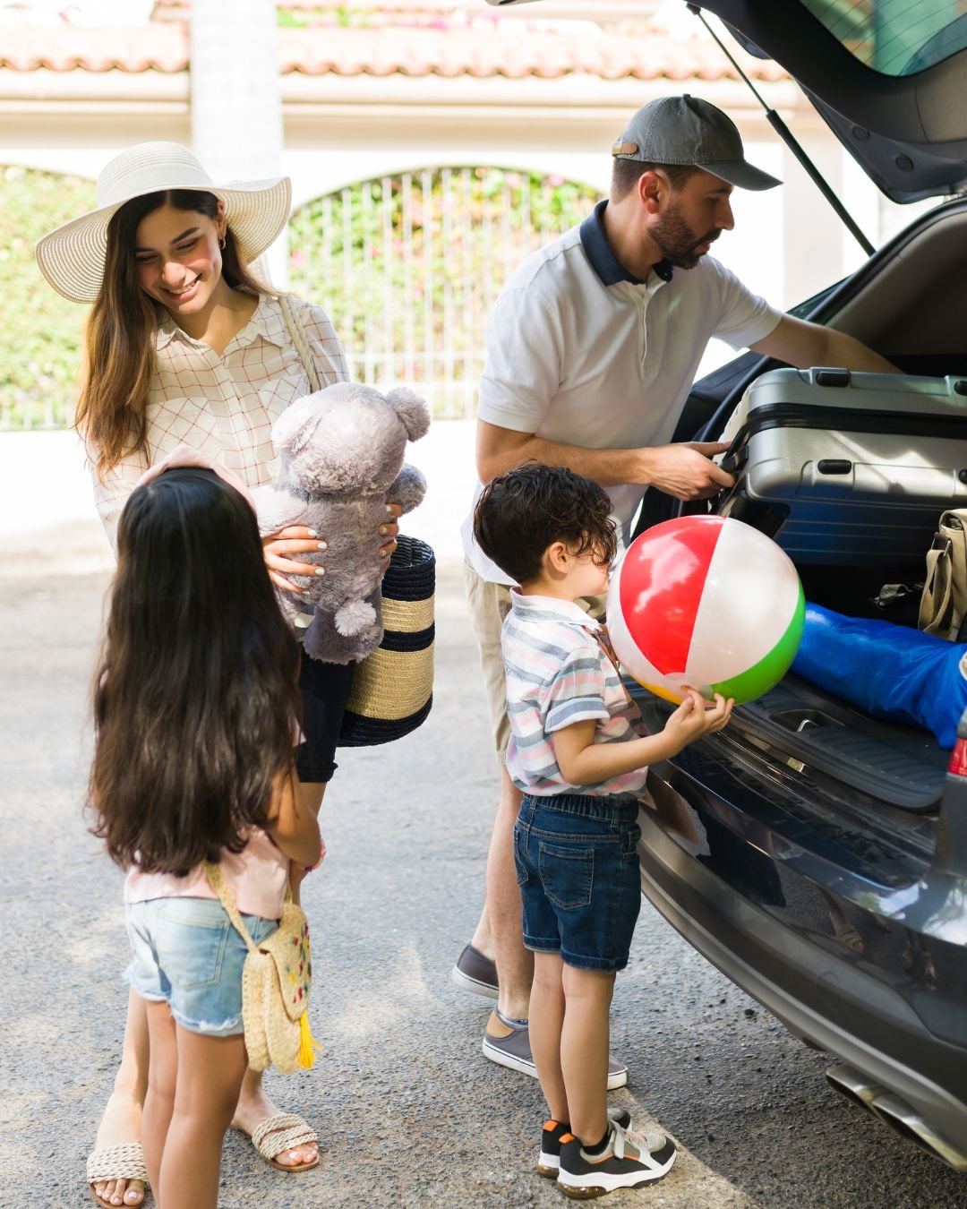 Family with kids loading car with luggage and pool toys