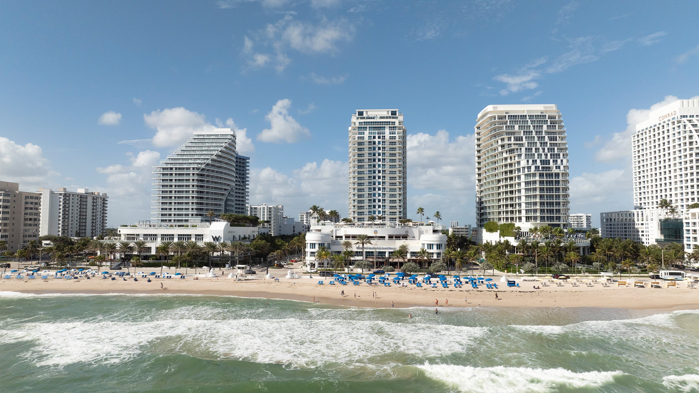 An overview of Fort Lauderdale beach with white buildings, parasols, tourists, etc.