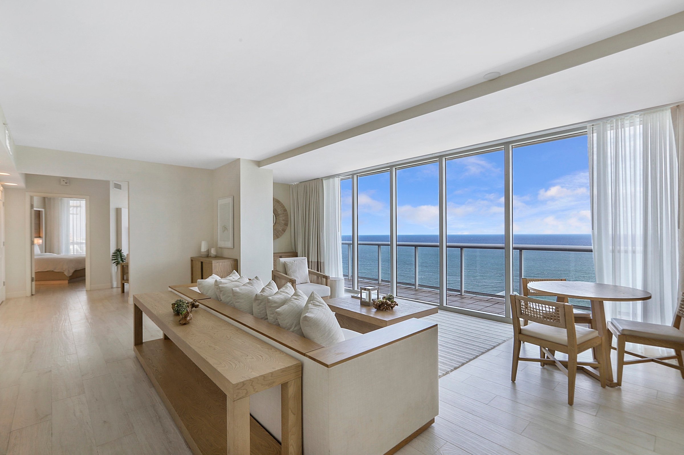 A bright living room with a large bay window overlooking the ocean
