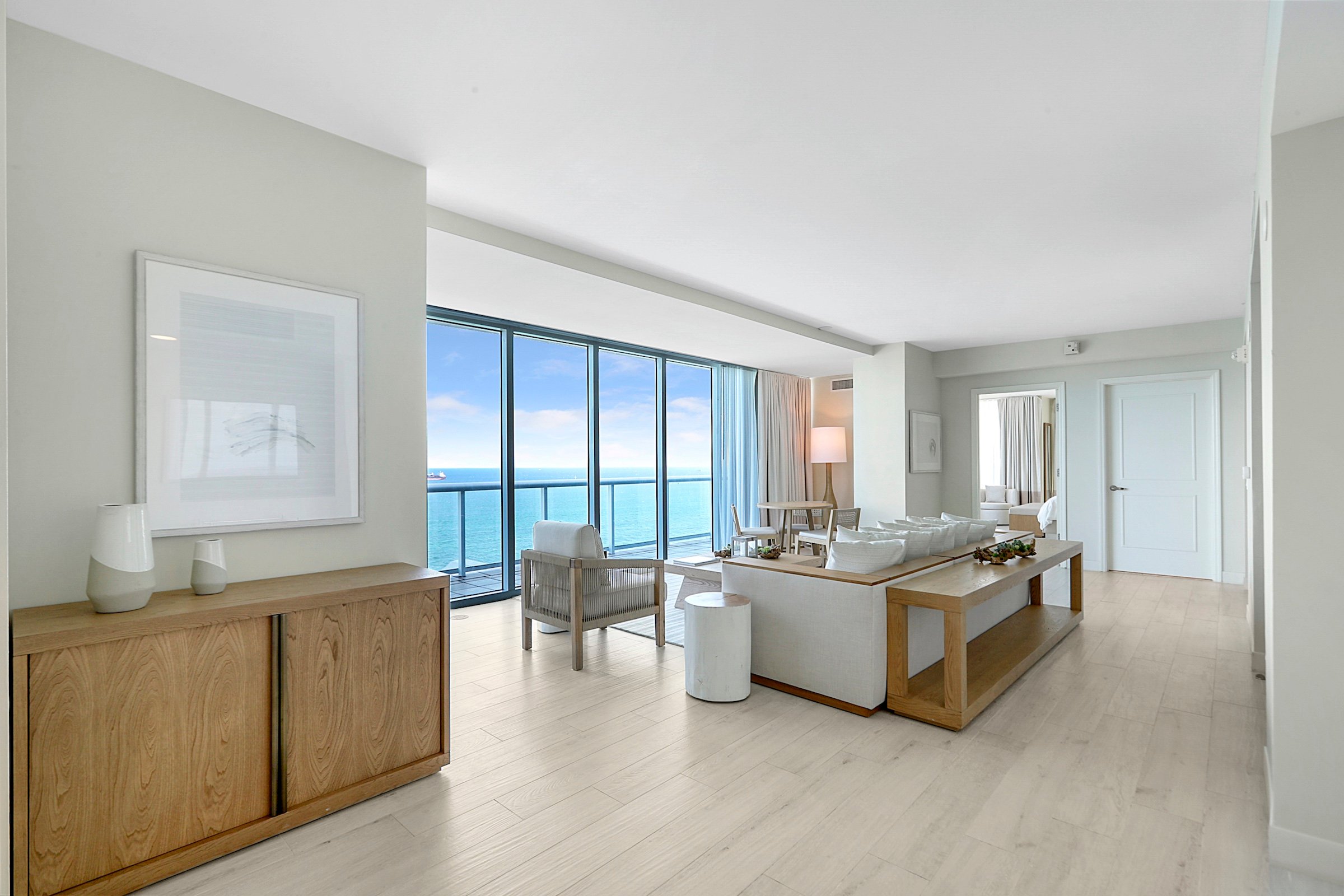 A bright living room with a large bay window overlooking the ocean