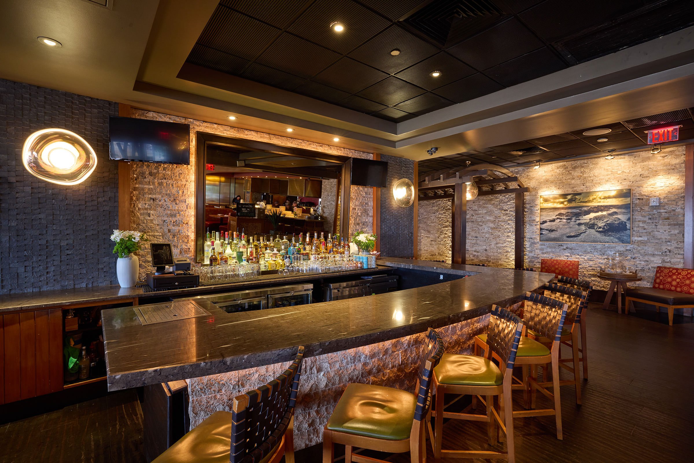 A large bartending space with selections of liquor and black marble table