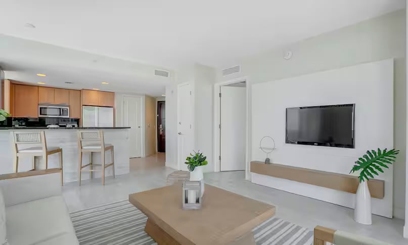 A large living room with white couch, light wooden tea table, and television