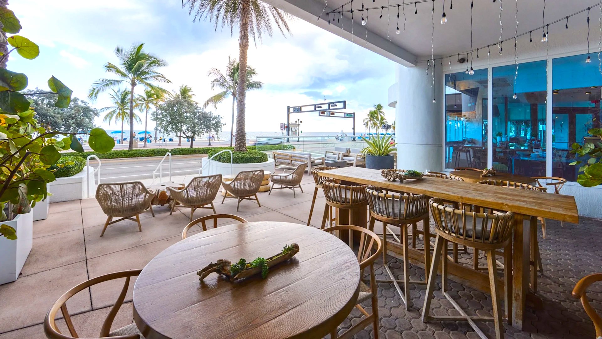 patio at le marche with wood tables and chairs across from the beach
