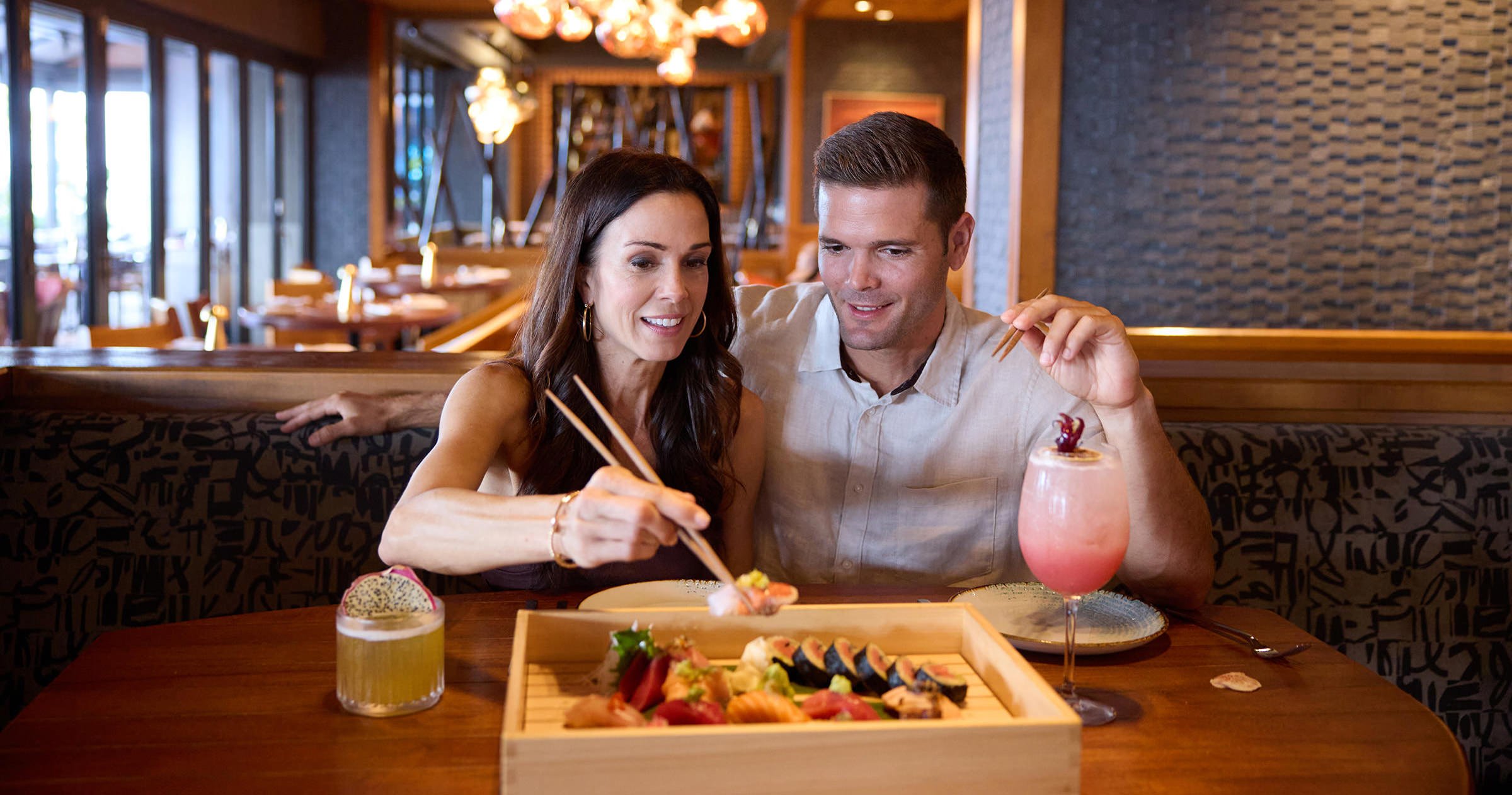 a couple enjoys cocktails and sushi
