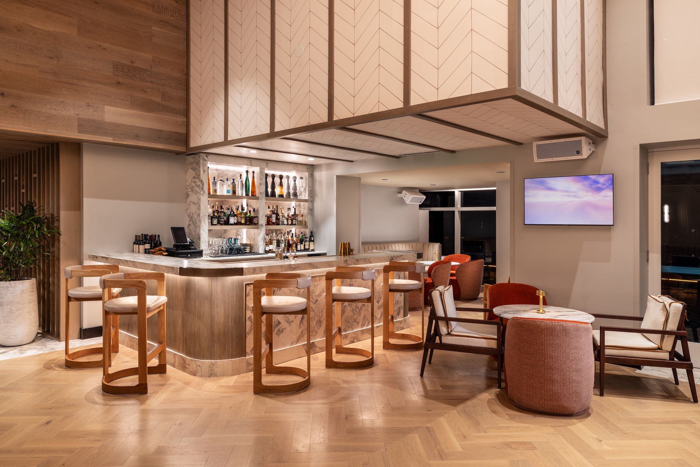 A trendy, modern corner bar surrounded by wooden bar stools
