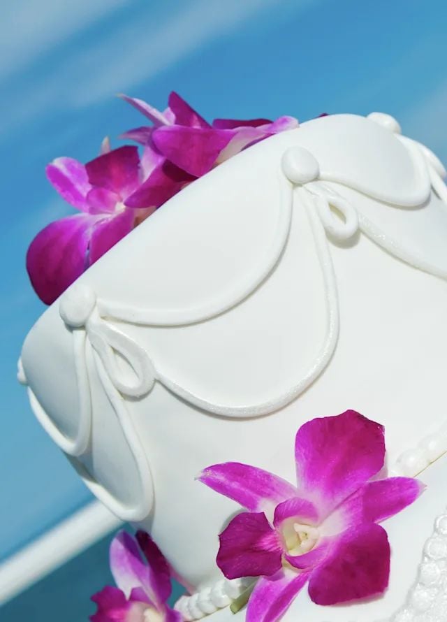 A tall white wedding cake topped with purple flowers