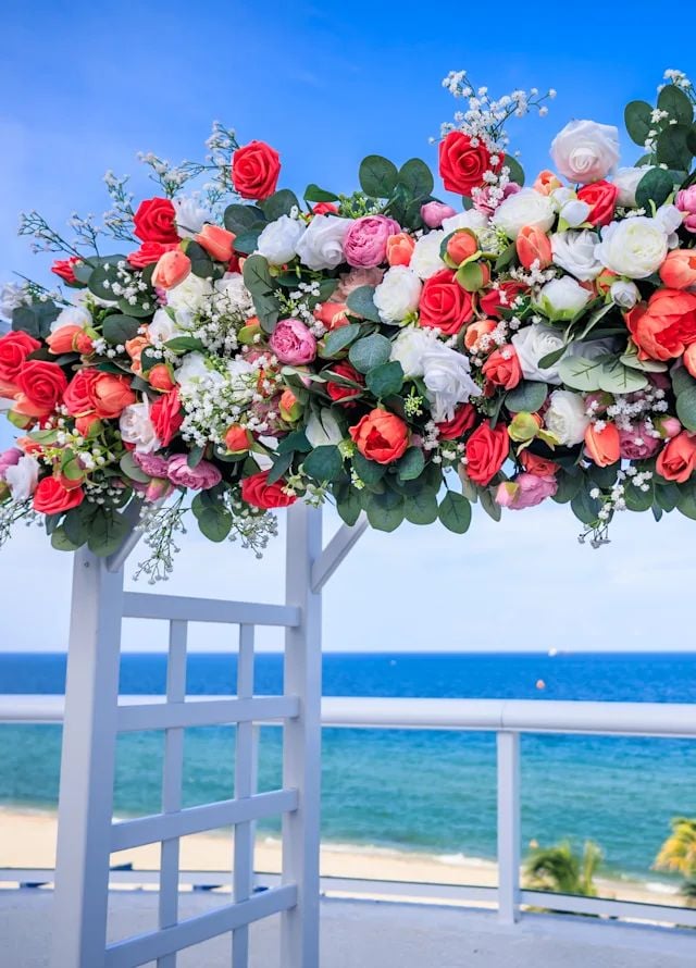 A wedding arch topped by flowers, by the sea