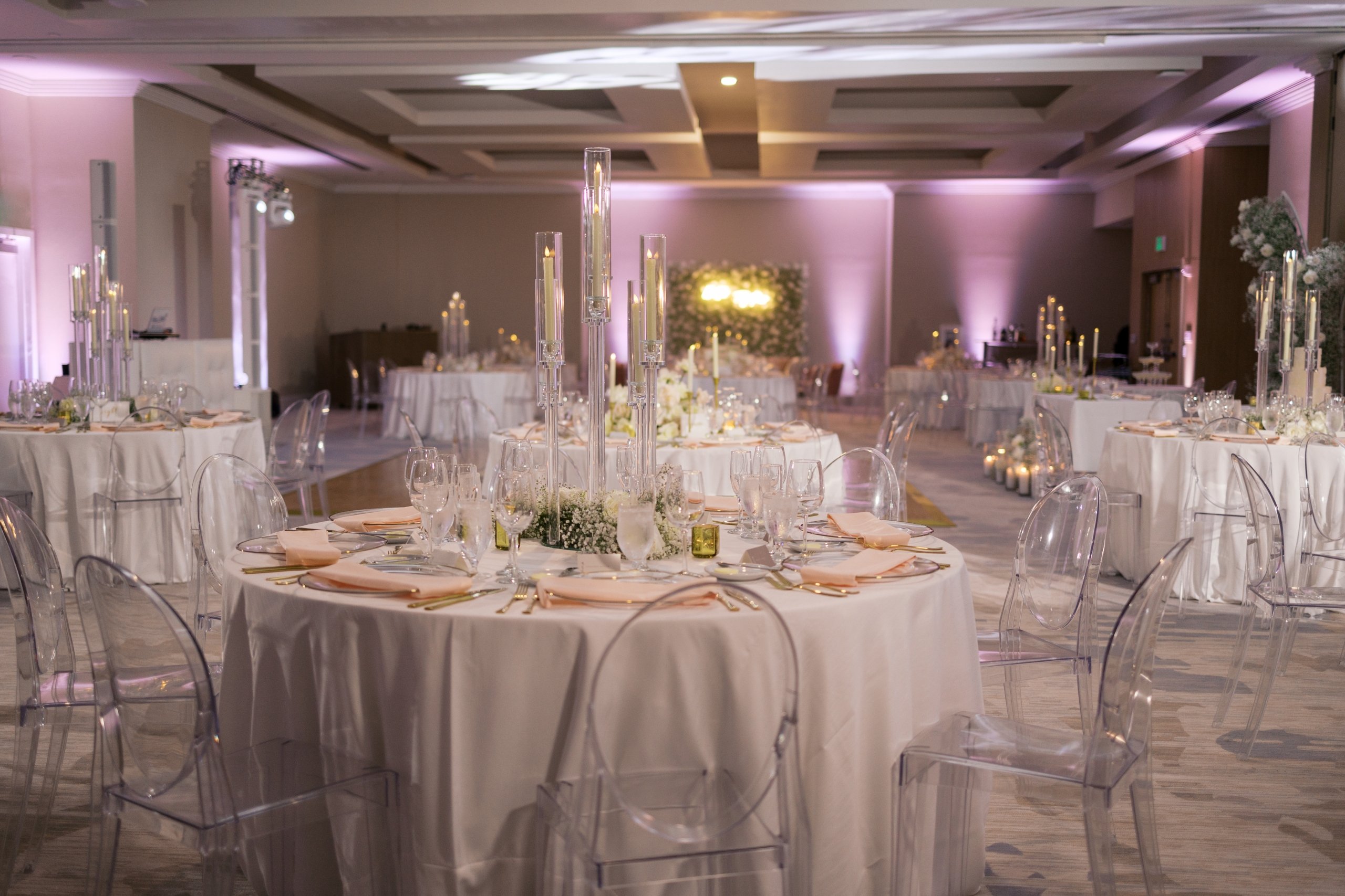 The Del Sol ballroom at the Beach House Fort Lauderdale, decorated with a wedding with elegant purple lighting and white linen-topped tables