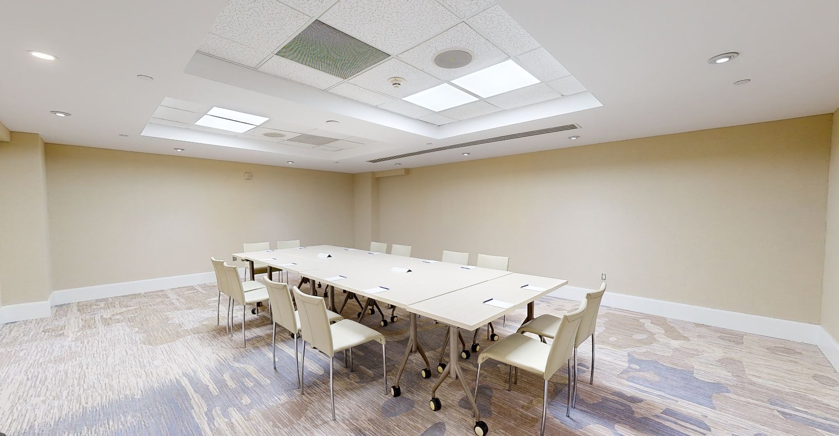 Beach House Fort Lauderdale Sonne meeting room, featuring a large television screen and a hollow square meeting table surrounded by chairs
