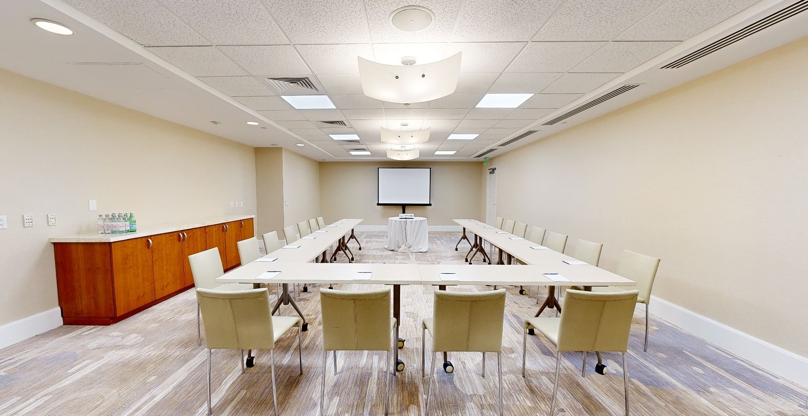 The Surya meeting room at Beach House Fort Lauderdale, with a sideboard, wall-mounted television and a semi circle table surrounded by chairs