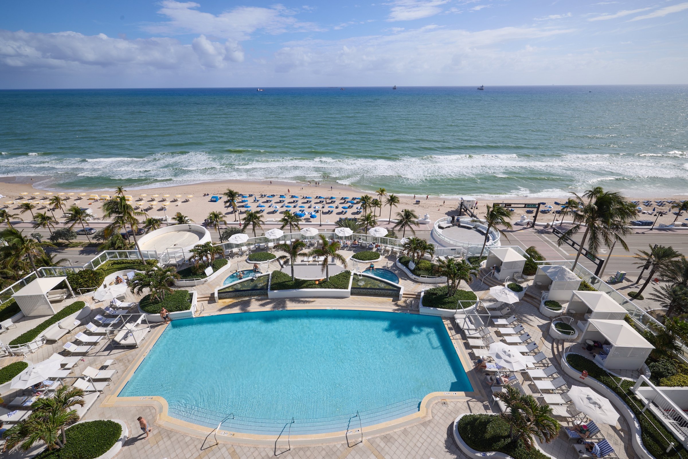 An aerial view of the pool, surrounding cabanas and oceanfront