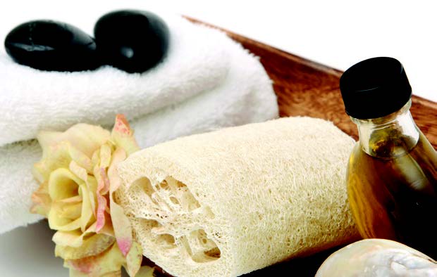 An assortment of spa amenities, including hot stones, fresh towels, a loofah and a bottle of oil