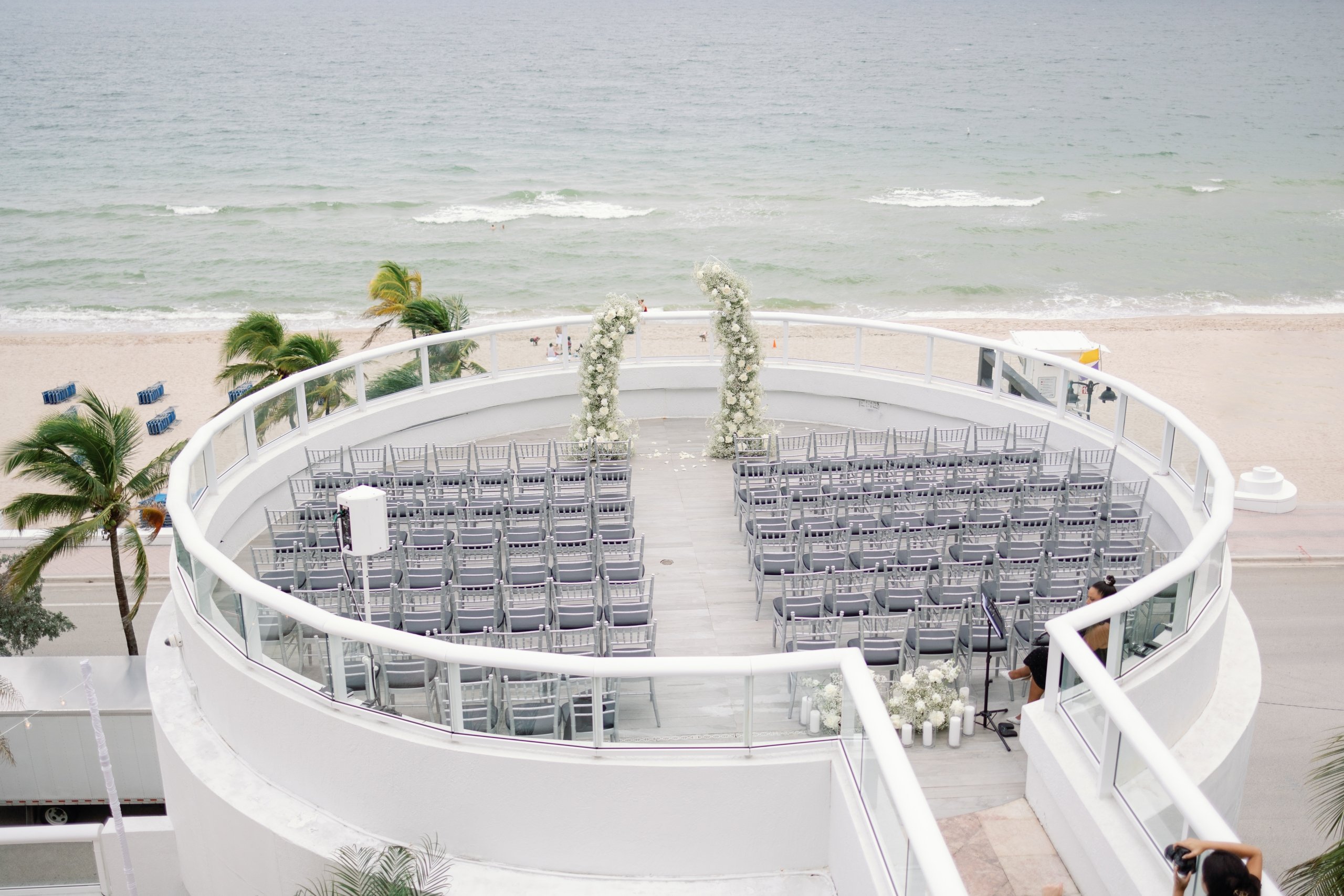 aerial view of a large circular balcony with silver chairs in preparation of a wedding ceremony