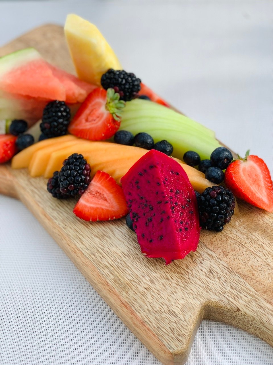 a wooden serving board with various cut fruit