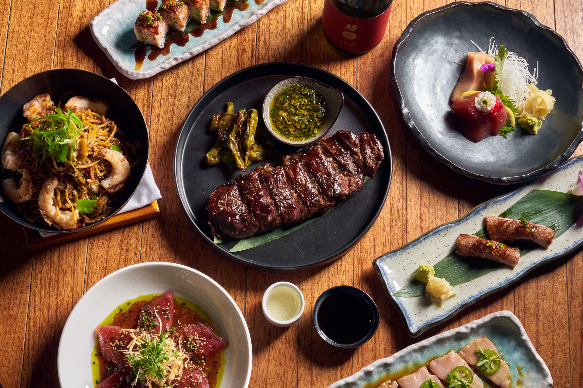 a top down view of various asian inspired dishes upon a wood table