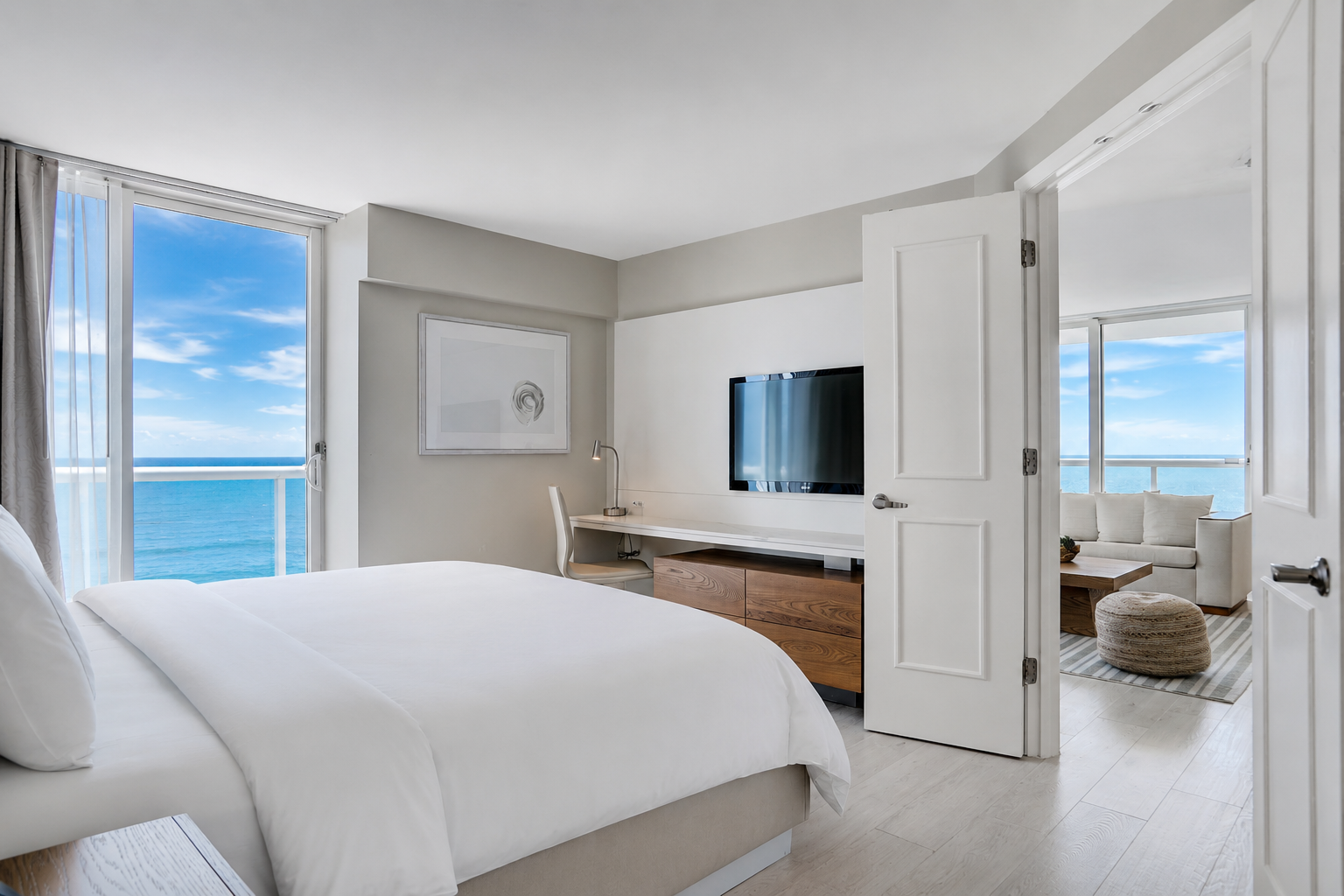 Bed and a glimpse of living room with balcony doors and a view of the ocean