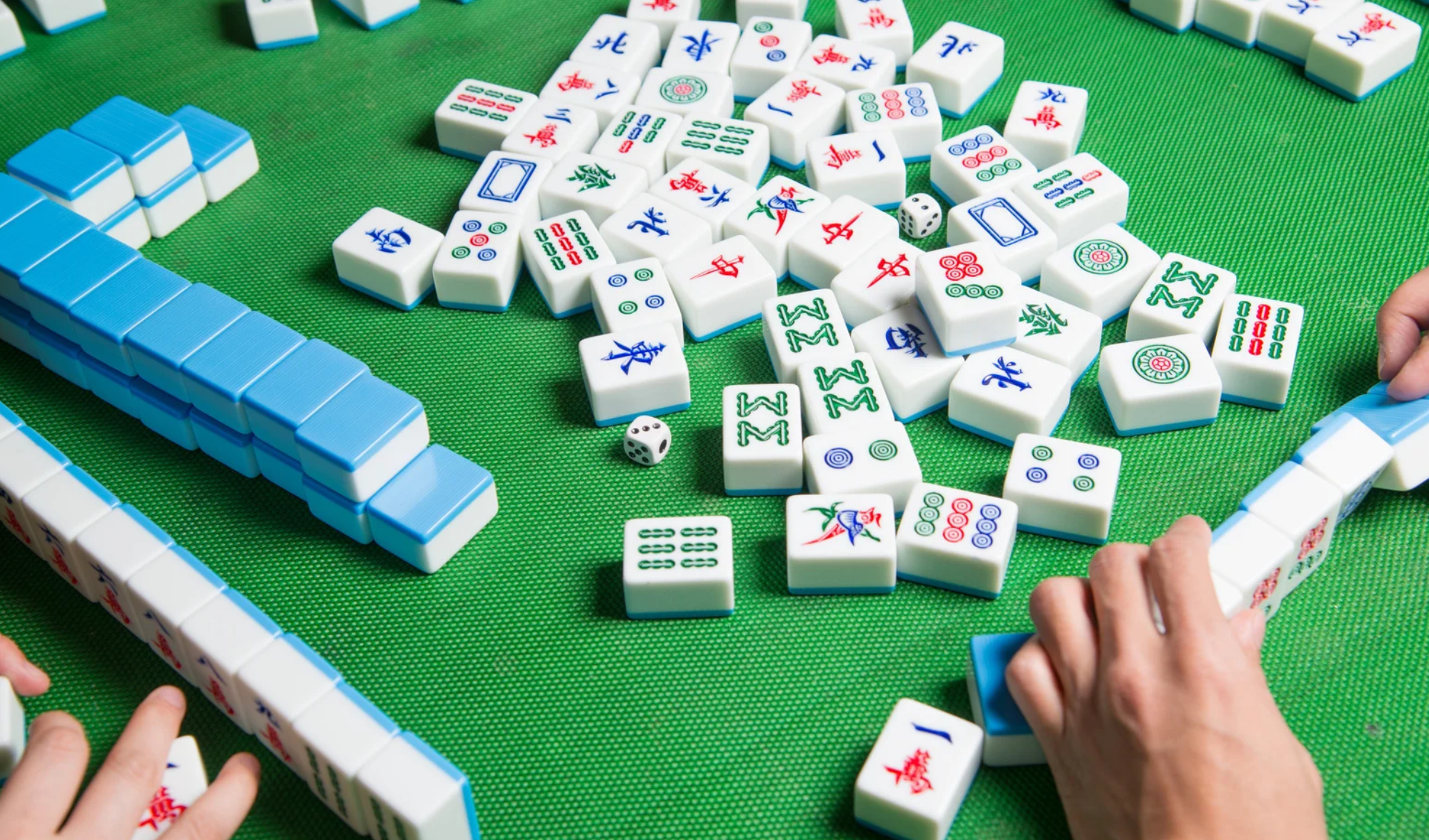 A pair of hands playing with mahjong tiles